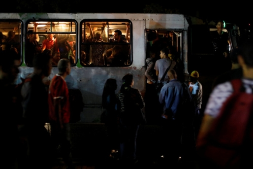 In het donker nemen mensen de bus tijdens de stroomuitval in Venezuela. © REUTERS