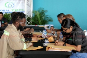 Ambtenaren van Global Tech helpen sollicitanten bij het invullen van formulieren tijdens hun banenbeurs in het C3 Center, San Fernando. De beurs is gericht op individuen die werk zoeken op de Guyaanse markt. -AYANNA KINSALE