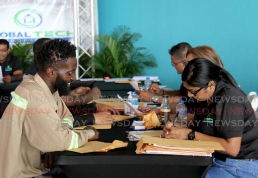 Ambtenaren van Global Tech helpen sollicitanten bij het invullen van formulieren tijdens hun banenbeurs in het C3 Center, San Fernando. De beurs is gericht op individuen die werk zoeken op de Guyaanse markt. -AYANNA KINSALE